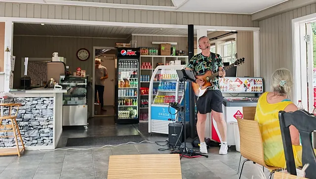 Mann spiller gitar i lokale
